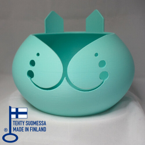 3D tulostettu pyöreä kulho, joka muistuttaa kissan kasvoja. Korvat on tulostettu takareunaan ja etureunassa on leveä kissamainen hymy
