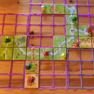 vasemmassa reunassa carcassonne-paloja aseteltuna, pääosan kuvasta täyttää eriväriset ruudukot, joihin mahtuu pelilaatta