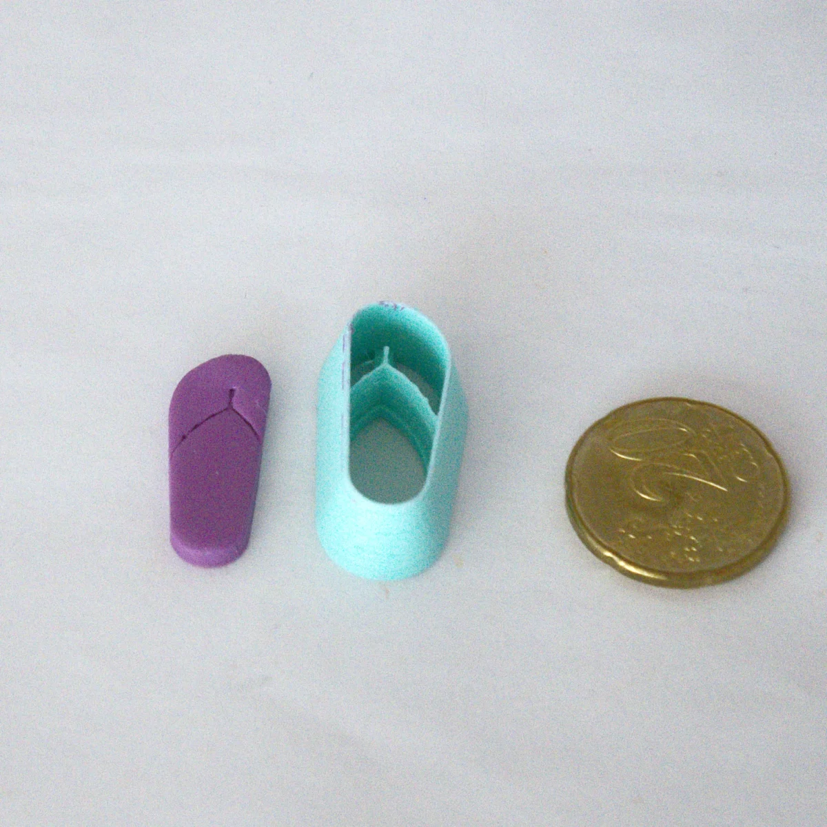 tavallinen flipflop leikattuna askartelumassasta, vasemmassa reunassa. keskellä leikkuri ja oikeassa reunassa 20snt kolikko