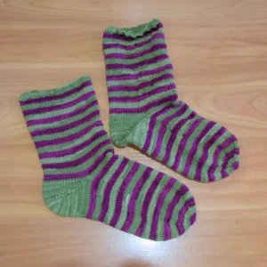 kaksi sukkaa, violetti-vihreä raidalliset. Alempi sukka on sileämpi kuin ylempi sukka